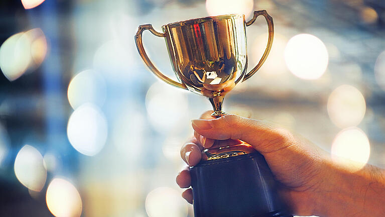 Hand hält einen Pokal