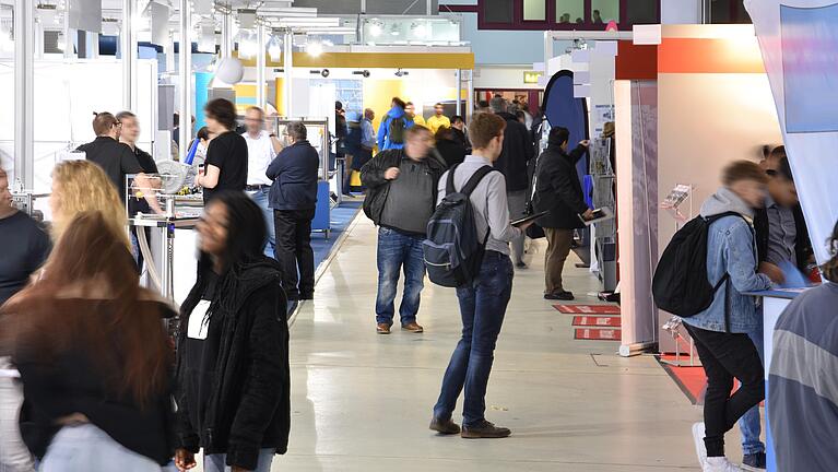 Personen auf einer Messe, Ansicht eines Gangs in einer Messehalle