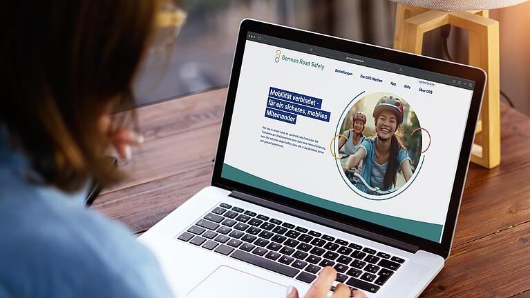 Sitzende Frau schaut auf den Bildschirm eines Laptops.